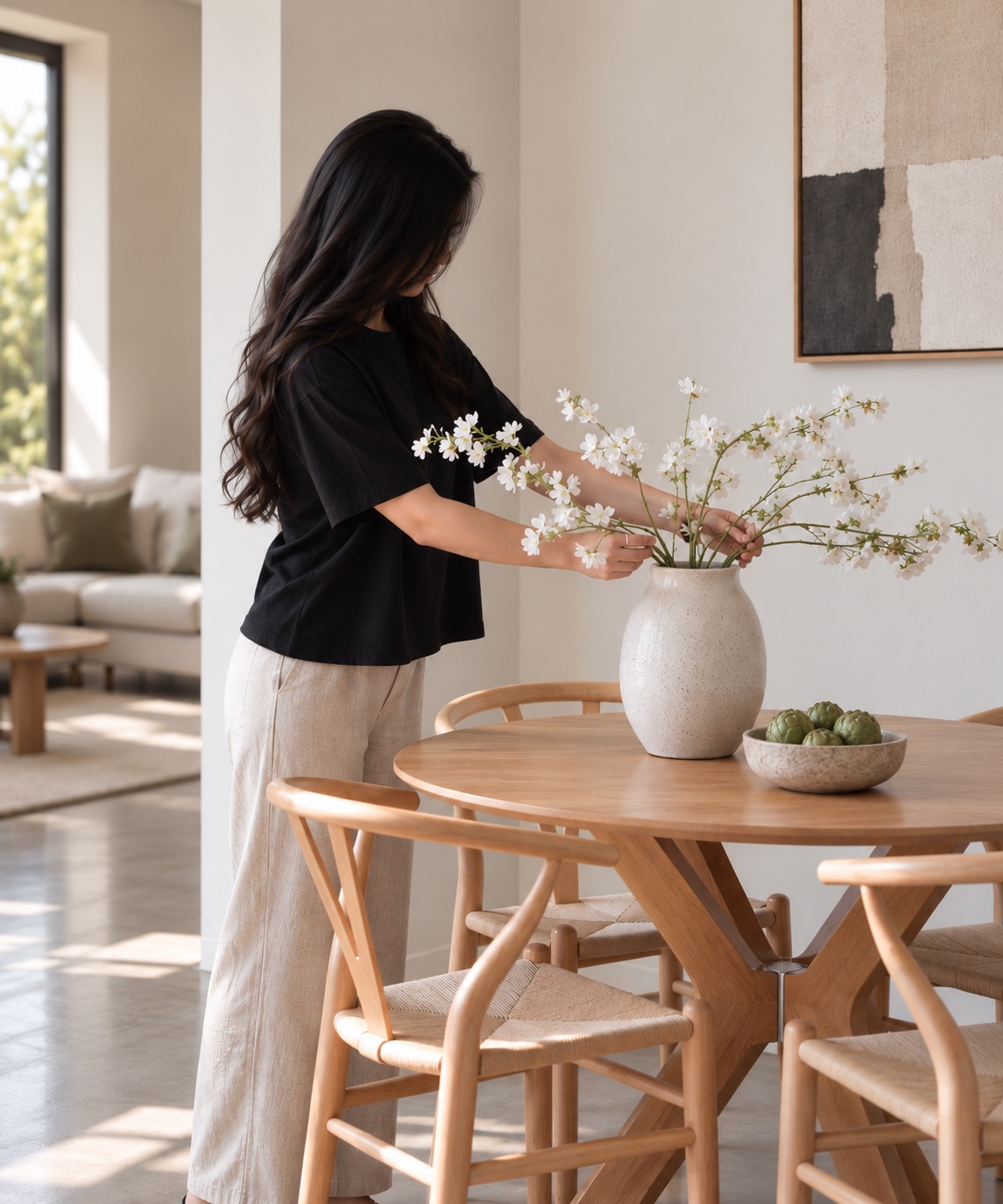 Property stylist arranging white flowers on a timber dining table before a home sale