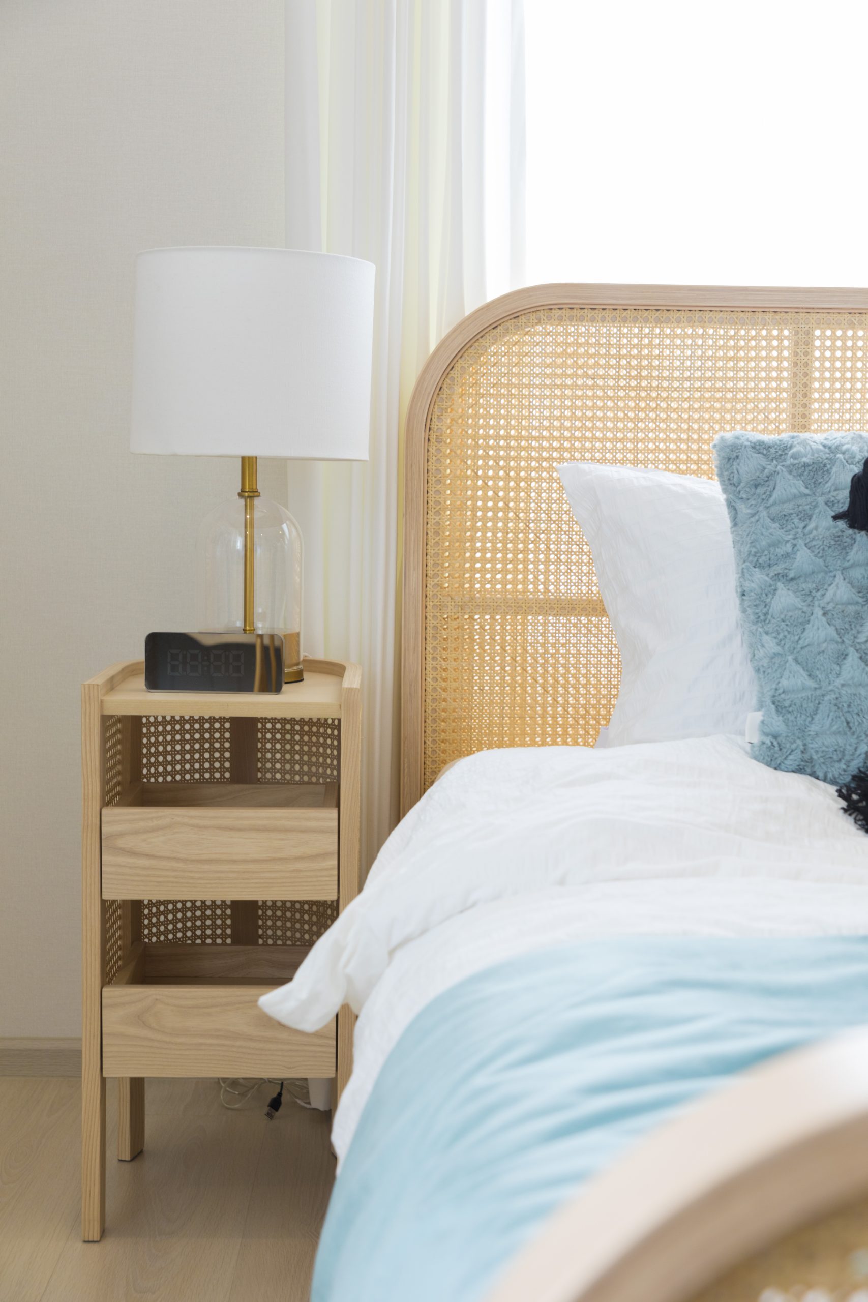 Close up of new comfortable bed with decorative pillows , wood headboard and side table lamp. Blue and orange scheme decoration.